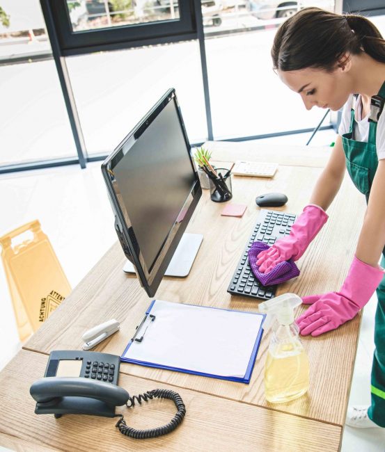 high angle view of young woman in rubber gloves cleaning office table